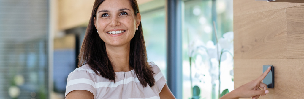 Frau bedient Loxone Touch zur smarten Haussteuerung
